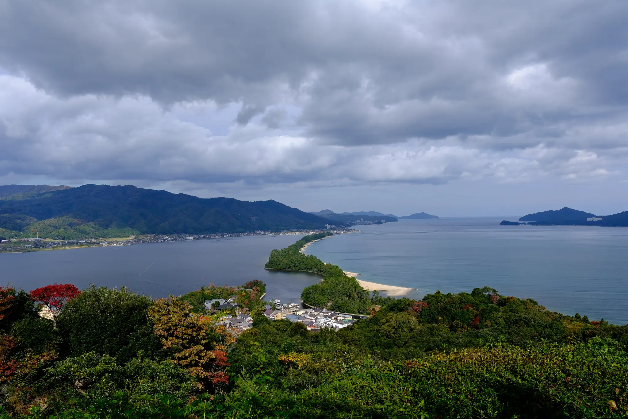 The pine-covered Amanohashidate sandbar stretching across the bay under heavy clouds