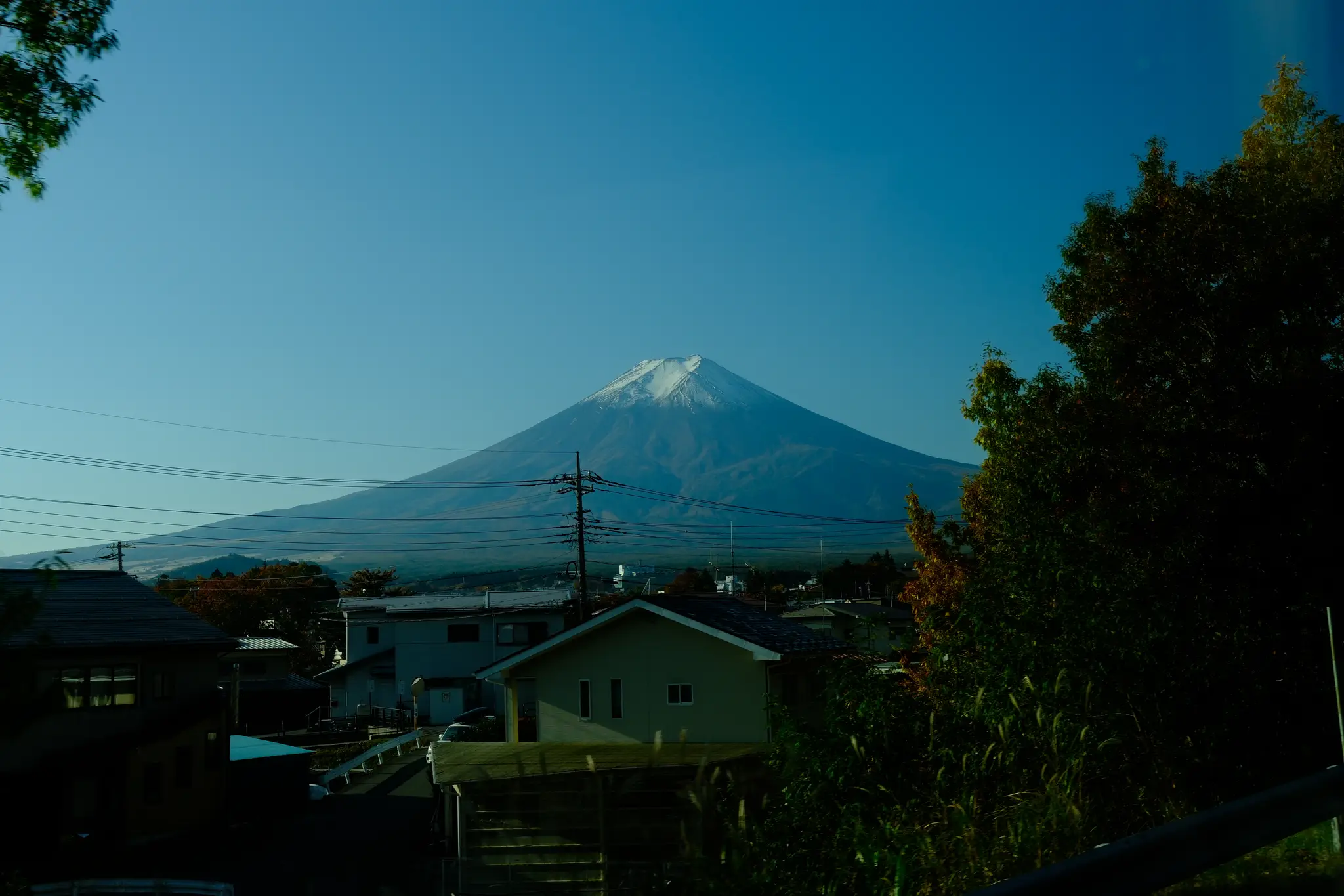 Mt. Fuji rising above village rooftops and trees in clear morning light