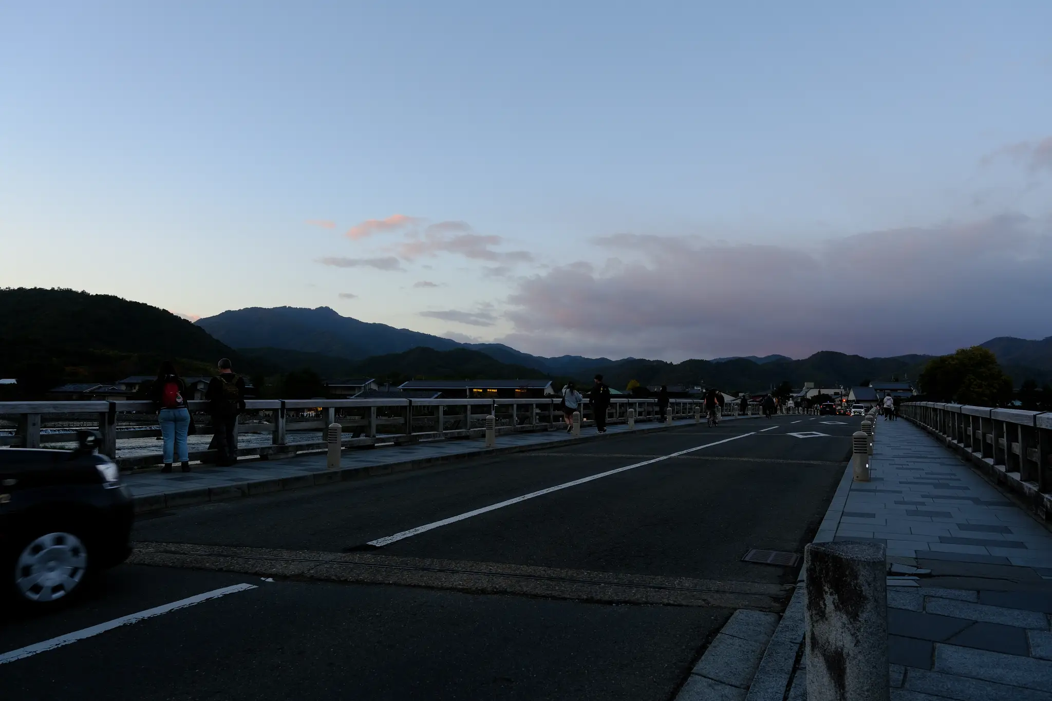The road across Togetsukyo Bridge with mountains at dusk